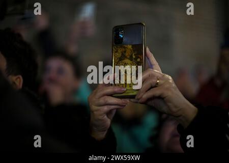 Madrid, Madrid, Espagne. 27 mars 2024. Une femme avec son téléphone portable qui a l'image du Christ de Medinaceli prend des photos du passage processionnel de l'image de notre Père de la santé à travers les rues de Madrid dans la nuit du mercredi Saint. (Crédit image : © Luis Soto/ZUMA Press Wire) USAGE ÉDITORIAL SEULEMENT! Non destiné à UN USAGE commercial ! Banque D'Images