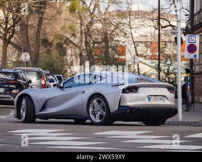 Strasbourg, France - 20 mars 2024 : une Ferrari sport argentée élégante conduisant sur le bord d'une route, reflétant la lumière du soleil, sans personne autour. Banque D'Images