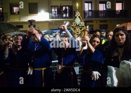 Les pénitents de la confrérie de Fusionadas sont vus faire des cloches devant les statues du Christ et de la Vierge, après que la procession a été suspendue en raison de la pluie, pendant le mercredi Saint, pour marquer les célébrations de la semaine Sainte. Des milliers de fidèles attendent pour voir les processions avec les statues du Christ et de la Vierge Marie dans le cadre des célébrations traditionnelles de la semaine Sainte. En Andalousie, Pâques rassemble des milliers de personnes du monde entier et est considérée comme l'un des événements religieux et culturels les plus importants de l'année. (Photo de Jesus Merida/SOPA images/SIPA USA) Banque D'Images