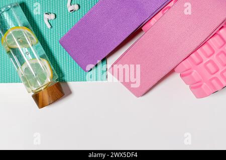 Accessoires d'entraînement et articles sur fond blanc, vue de dessus. Bouteille d'eau et bandes de résistance Banque D'Images