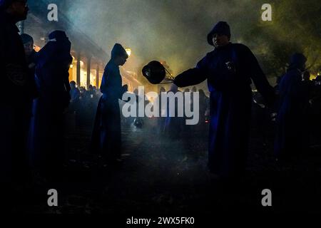 Antigua, Guatemala. 27 mars 2024. Les pénitents utilisent des centreurs pour répandre de l'encens devant le massif flotteur processionnel Jesús Nazareno del Milagro pendant la traditionnelle Santa Semana célébrant la semaine Sainte, le 27 mars 2024 à Antigua, Guatemala. Les processions opulentes, les algèbres détaillées et les traditions séculaires attirent plus d'un million de personnes dans l'ancienne capitale. Crédit : Richard Ellis/Richard Ellis/Alamy Live News Banque D'Images