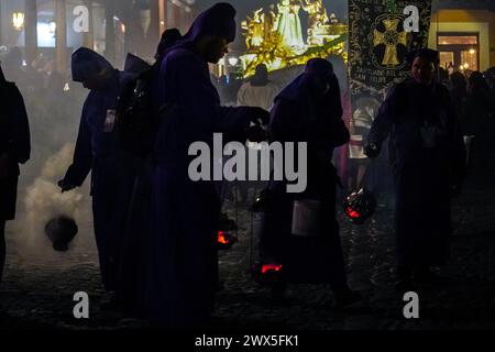 Antigua, Guatemala. 27 mars 2024. Les pénitents utilisent des centreurs pour répandre de l'encens devant le massif flotteur processionnel Jesús Nazareno del Milagro pendant la traditionnelle Santa Semana célébrant la semaine Sainte, le 27 mars 2024 à Antigua, Guatemala. Les processions opulentes, les algèbres détaillées et les traditions séculaires attirent plus d'un million de personnes dans l'ancienne capitale. Crédit : Richard Ellis/Richard Ellis/Alamy Live News Banque D'Images