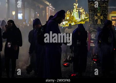 Antigua, Guatemala. 27 mars 2024. Les pénitents utilisent des centreurs pour répandre de l'encens devant le massif flotteur processionnel Jesús Nazareno del Milagro pendant la traditionnelle Santa Semana célébrant la semaine Sainte, le 27 mars 2024 à Antigua, Guatemala. Les processions opulentes, les algèbres détaillées et les traditions séculaires attirent plus d'un million de personnes dans l'ancienne capitale. Crédit : Richard Ellis/Richard Ellis/Alamy Live News Banque D'Images