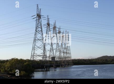 Tours électriques avec lignes électriques à côté d'une rivière d'eau Banque D'Images