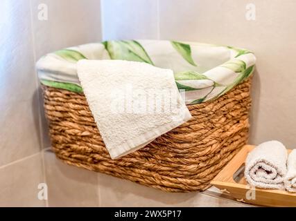 panier en osier en bois avec serviettes sur étagère en bois pour salle de bain Banque D'Images