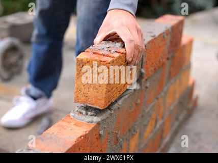 Maçon, main et construction avec homme constructeur sur le toit, employé travaillant dans l'industrie industrielle et carrière d'entrepreneur. Extérieur, ciment sur place Banque D'Images