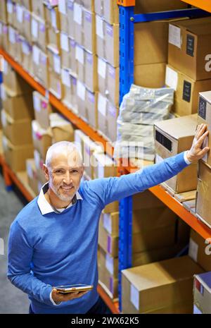 Vue de dessus, boîte ou portrait de l'homme dans l'entrepôt pour l'étiquette d'ordre de livraison, le stockage ou le stock en usine avec tablette. Impression, gestionnaire mature heureux ou Banque D'Images