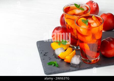 Peach thé glacé dans un verre à la menthe sur une table en bois blanc(selective focus). Banque D'Images