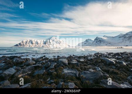 Paysage pittoresque de la plage de Skagsanden avec chaîne de montagnes enneigée sur le bord de mer en hiver aux îles Lofoten, Norvège Banque D'Images