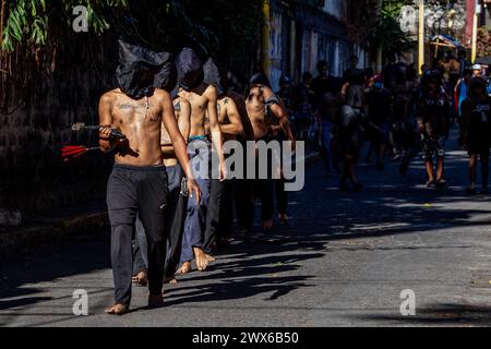 Mandaluyong City, Philippines. 28 mars 2024. Les flagellants philippins marchent le long d'une rue dans la ville de Mandaluyong. Beaucoup de dévots catholiques philippins passent leur semaine Sainte en faisant différentes formes de pénitence physique pour se repentir de leurs péchés. Crédit : SOPA images Limited/Alamy Live News Banque D'Images