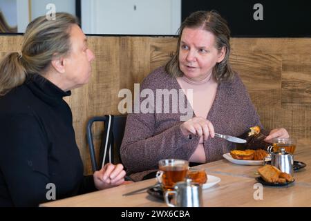 Deux femmes matures mangeant des torrijas espagnols typiques pour Pâques dans une cafétéria tout en parlant Banque D'Images