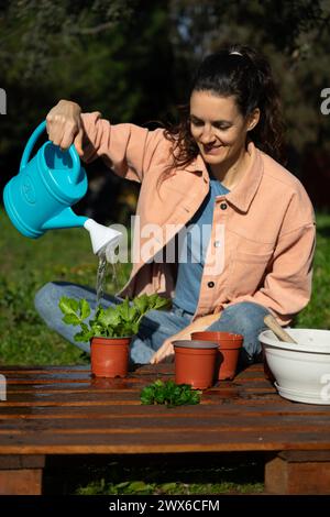 Femme arrosant une plante nouvellement plantée dans un pot pour faire un jardin Banque D'Images