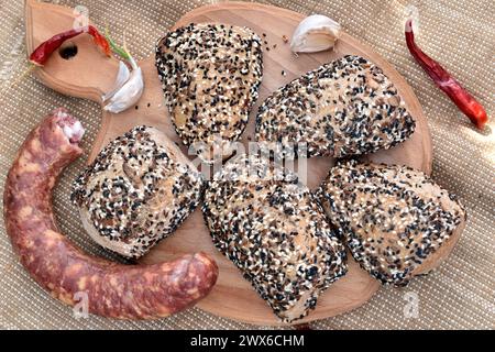 Du pain cuit avec des graines et des saucisses repose sur la table. Banque D'Images