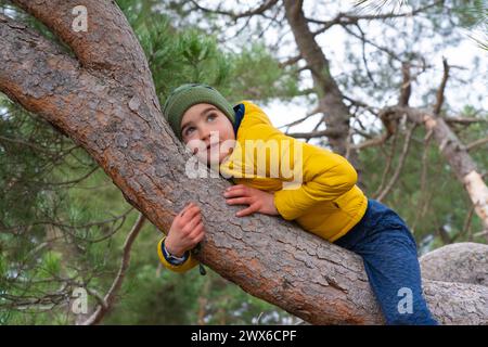 Garçon couché sur un tronc d'arbre Banque D'Images