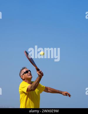 Homme senior avec style de vie actif jouant au tennis de plage en vacances Banque D'Images