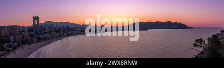 La photographie capture la beauté tranquille d'un lever de soleil panoramique sur Benidorm, en Espagne. Dans la lumière tôt le matin, le paysage urbain prend vie avec un Banque D'Images