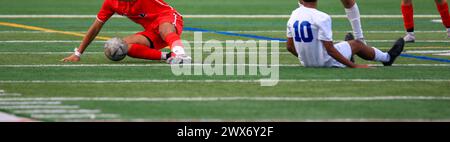 Joueurs de football tombant alors qu'ils pourchassaient un ballon de football pendant un match sur un terrain de gazon. Banque D'Images