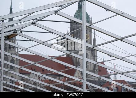 Munich, Allemagne. 28 mars 2024. Les ouvriers ont installé une tente de bière pour le festival de printemps sous la pluie sur la Theresienwiese. Prog L'église de Paul peut être vue à l'arrière-plan. La fête du printemps a lieu à partir du 19.04. - 05.05.2024. Crédit : Sven Hoppe/dpa/Alamy Live News Banque D'Images