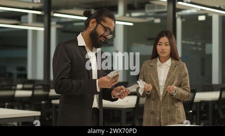 Inégalité salaire égal discrimination raciale genre monde patriarcal Indien homme d'affaires asiatique femme au bureau comptant argent finance salaire cash Banque D'Images