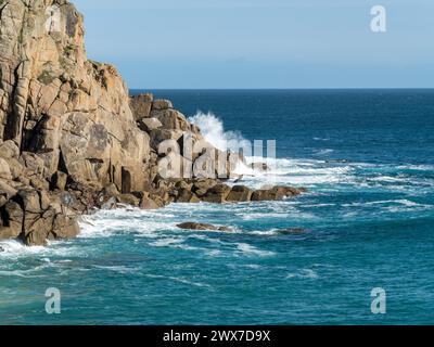 Vagues se brisant sur le promontoire rocheux de granit de Cornouailles près de Porthcurno par une journée ensoleillée avec un ciel bleu clair, Cornouailles, Angleterre, Royaume-Uni Banque D'Images