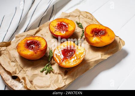 Pêches cuites au four avec du miel et de la cannelle sur fond de bois blanc. dessert d'été. Banque D'Images