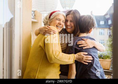 Femme heureuse embrassant belle-mère et fils tout en se tenant dans le balcon Banque D'Images