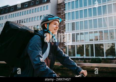 Motard féminin souriant portant un casque et le vélo en ville Banque D'Images