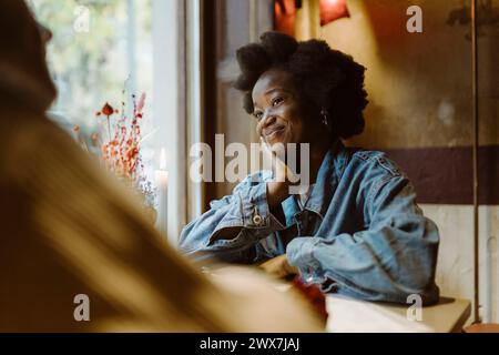 Femme souriante appuyée sur le coude et regardant son petit ami assis au bar Banque D'Images