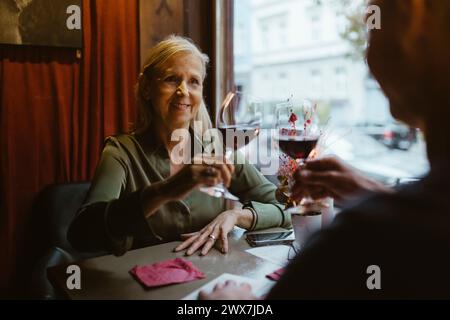 Femme souriante griller un verre de vin avec l'homme à la date au restaurant Banque D'Images