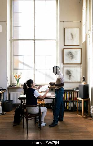 Collègues masculins et féminins multiraciaux discutant sur le document dans l'atelier Banque D'Images
