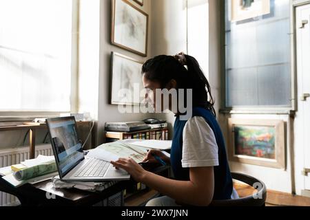 Femme d'affaires utilisant un ordinateur portable sur la table tout en travaillant à la maison Banque D'Images