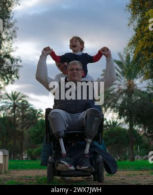 être dans un fauteuil roulant n'est pas un problème pour ce père de porter un sourire sur le visage de sa famille. Banque D'Images