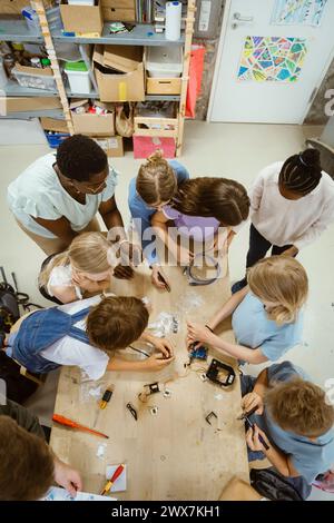 Vue en angle élevé des élèves hommes et femmes travaillant sur un projet de robotique avec un enseignant en classe à l'école Banque D'Images