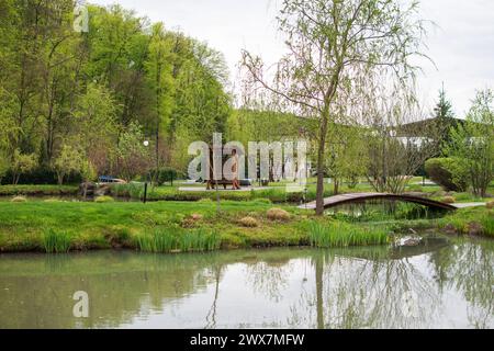 La belle vue sur le parc avec les arbres, terrain d'herbe verte, gazebo et l'étang sur le fond de ciel bleu et de nuages blancs, printemps Banque D'Images