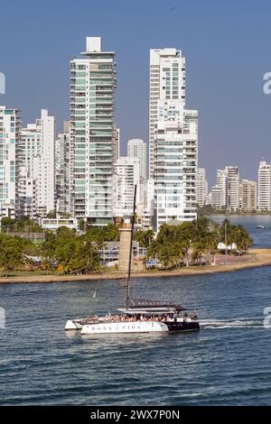 Carthagène, Colombie - 24 janvier 2024 : catamaran avec des touristes naviguant devant le club naval et le phare à l'entrée du port de la ville Banque D'Images