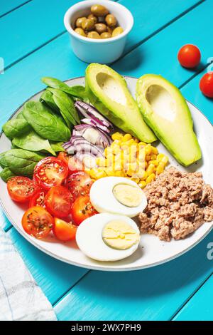 Bol à lunch sain : oeuf, thon, avocat, tomates cerises, salade de maïs, oignon. Banque D'Images