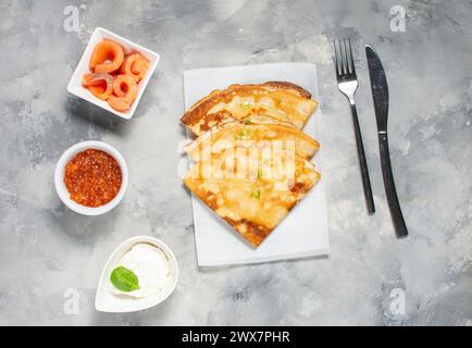 Fines crêpes russes ou blini au caviar rouge et au saumon sur une table en béton. Vue de dessus. Banque D'Images