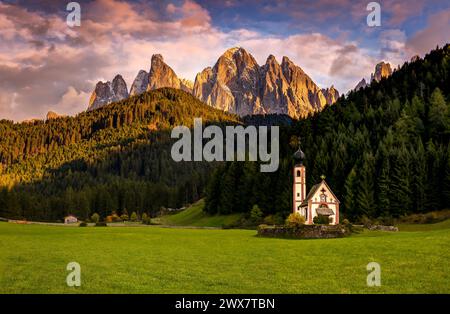 Une photo de coucher de soleil de la chapelle de Sankt Johann à Ranui dans le village de Santa Magdalena dans le Val di Funes dans la région des Dolomites en Italie Banque D'Images