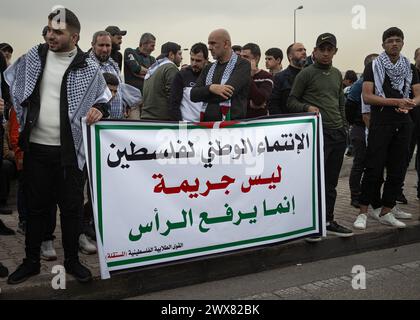 Beyrouth, Liban. 27 mars 2024. Des hommes palestiniens tiennent une banderole disant « L’appartenance nationale à la Palestine n’est pas un crime, mais cela garde la tête haute » lors d’une manifestation à Beyrouth, Liban, le 27 mars 2024 contre le traitement présumé de l’UNRWA à ses employés pro-palestiniens. (Photo de Collin Mayfield/Sipa USA) crédit : Sipa USA/Alamy Live News Banque D'Images