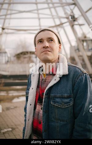 Homme debout devant la grande roue. Un homme se tient devant une grande grande roue dans un parc d'attractions. Banque D'Images
