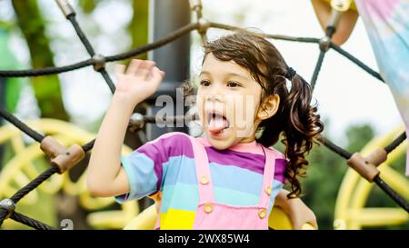 Jeune fille avec la bouche agape attrapée dans le filet de corde à l'aire de jeux Banque D'Images