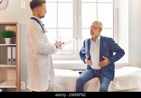 Médecin consultant un patient senior masculin parlant, partageant des symptômes de l'estomac, se plaignant du ventre Banque D'Images