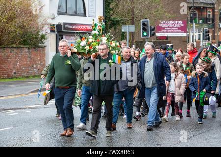 Quatre hommes portent une statue fleurie de St Patrick lors de la parade de la St Patrick en 2024 à Warrington Banque D'Images