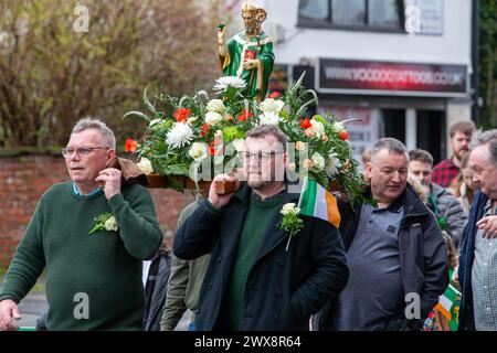 Quatre hommes portent une statue fleurie de St Patrick lors de la parade de la St Patrick en 2024 à Warrington Banque D'Images