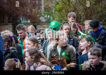 Une dame blonde portant un chapeau Leprechaun marche avec la foule pendant la parade de la St Patrick de Warrington en 2024 Banque D'Images