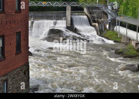 SHERBROOKE, QUÉBEC, CANADA - 6 MAI 2022 - rivière Magog barrage de la centrale hydroélectrique Sherbrooke Abenakis. Grande conduite forcée blanche et passerelle Banque D'Images