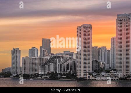 Miami, Floride, USA - 29 juillet 2023 : ciel orange au-dessus des bâtiments sur l'île de Brickell Key au soir 19:43. La statue Centinel entre Tequesta pointe Banque D'Images