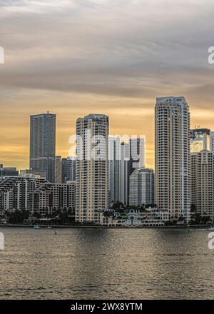 Miami, Floride, États-Unis - 29 juillet 2023 : Portrait. Ciel gris à jaune au-dessus des bâtiments sur l'île de Brickell Key au soir 19:47. Statue de Centinel entre deux Banque D'Images