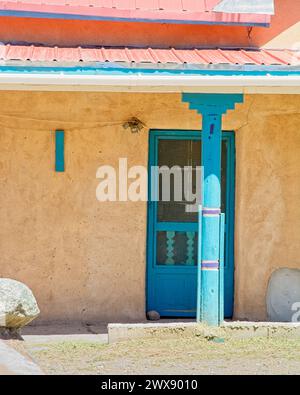 La colonne en bois colorée tient le toit de portail revêtu d'étain de la maison adobe Banque D'Images