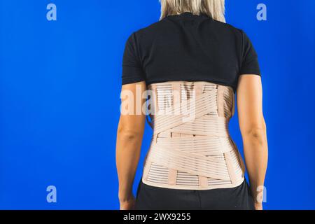 Attelle lombaire sur le corps humain isolée sur fond bleu. Traumatisme du dos. Attelle dorsale, lombaire orthopédique, ceinture de soutien pour les muscles du dos. Problèmes de bas du dos. Photo de haute qualité Banque D'Images